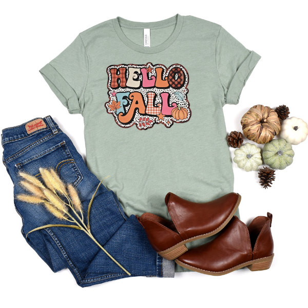 A green t-shirt with 'HELLO FALL' text and colorful polka dots design, paired with blue jeans and brown ankle boots.